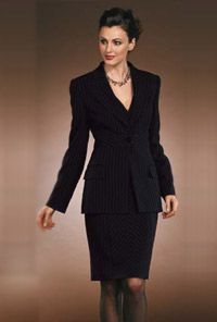 Frau in einem dunkel gestreiften Kostüm, Jacke zugeknöpft, Rock knielang, vor neutralem Hintergrund.