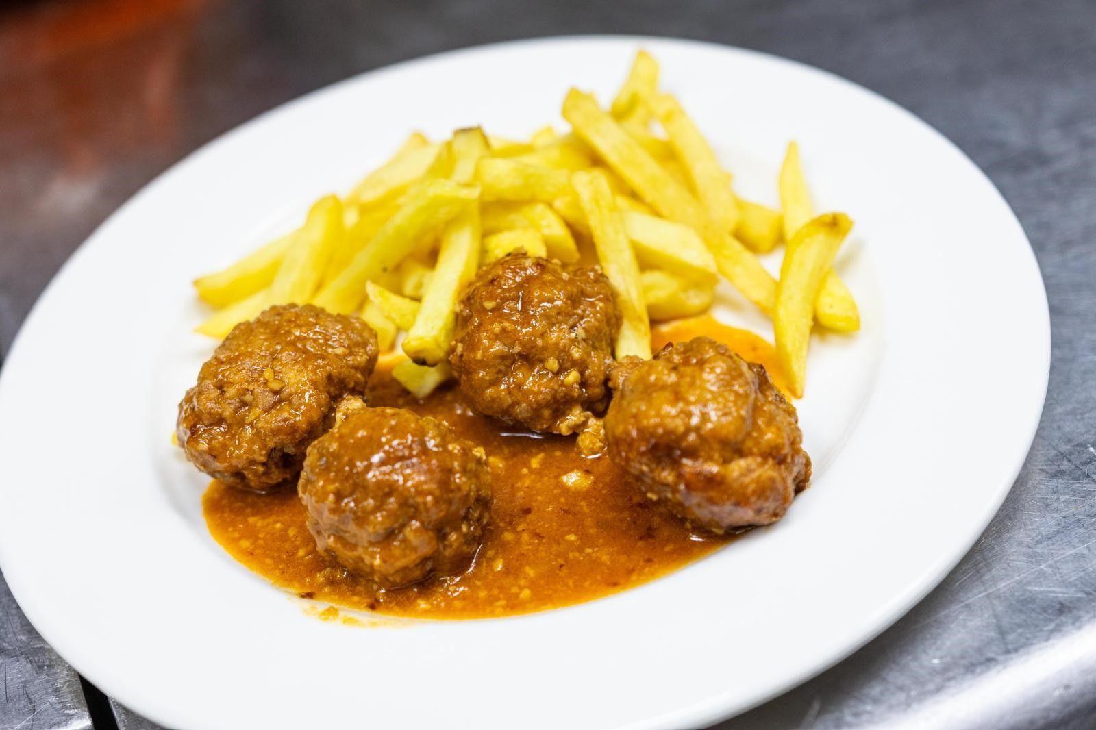 Un plato con varias albóndigas doradas cubiertas con una sabrosa salsa de naranja.