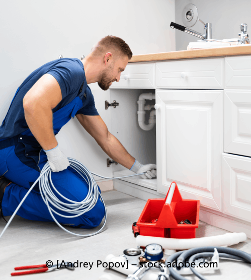 Ein Mann kniet auf dem Boden und repariert ein Spülbecken in einer Küche. R & I Felber Service GmbH