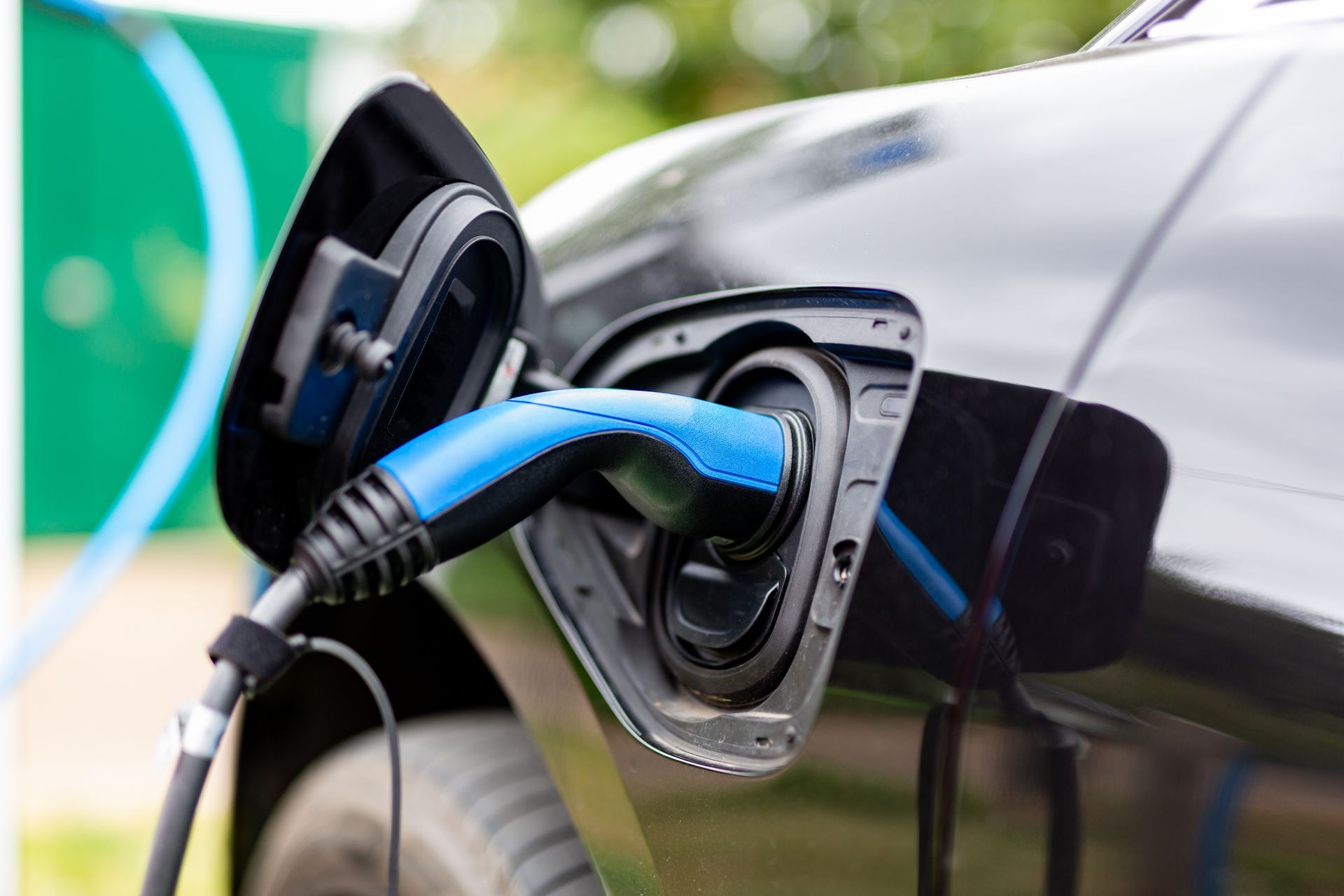 Prise de recharge pour voiture électrique connectée à un véhicule noir à une borne de recharge.