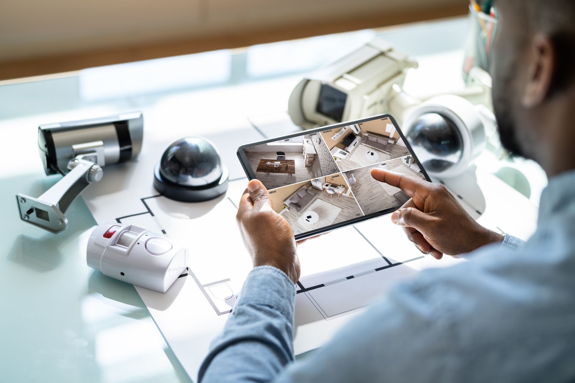 Une personne utilise une tablette pour visionner les images d'une caméra de sécurité domestique posée sur un bureau.