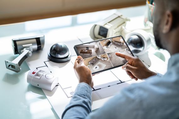 Une personne utilise une tablette pour visionner les images d'une caméra de sécurité domestique posée sur un bureau.