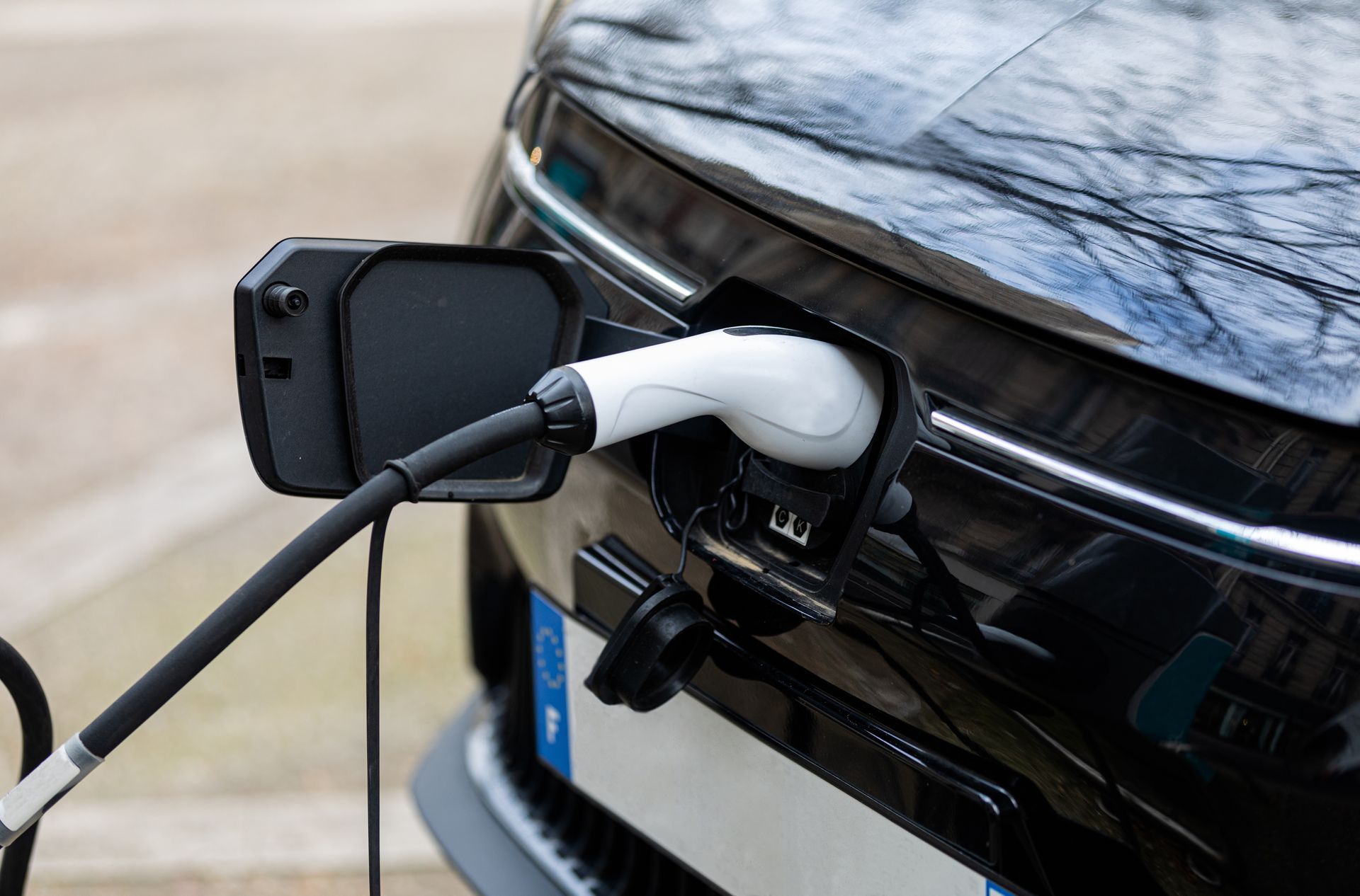 Câble de recharge pour voiture électrique branché à un véhicule noir à une station de recharge