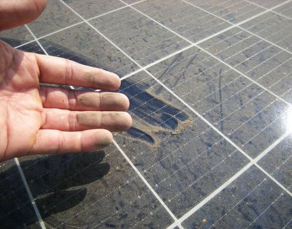 Una persona con guantes amarillos instala un panel solar en un techo de tejas.