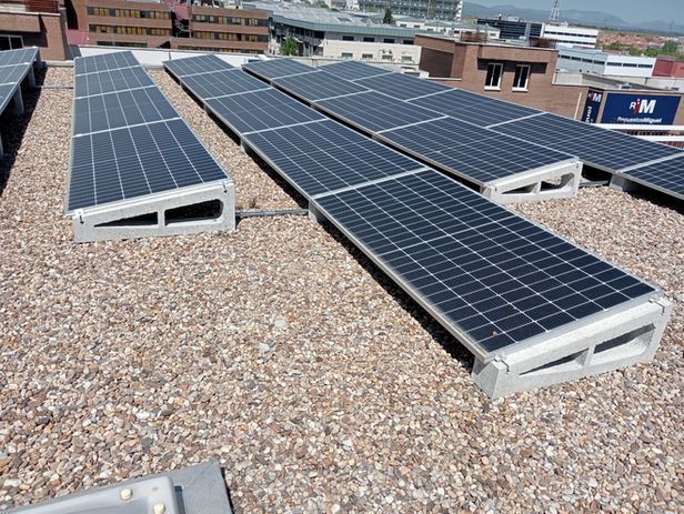 Estación de carga de vehículos eléctricos con energía solar con automóviles estacionados y cargándose en un día soleado.