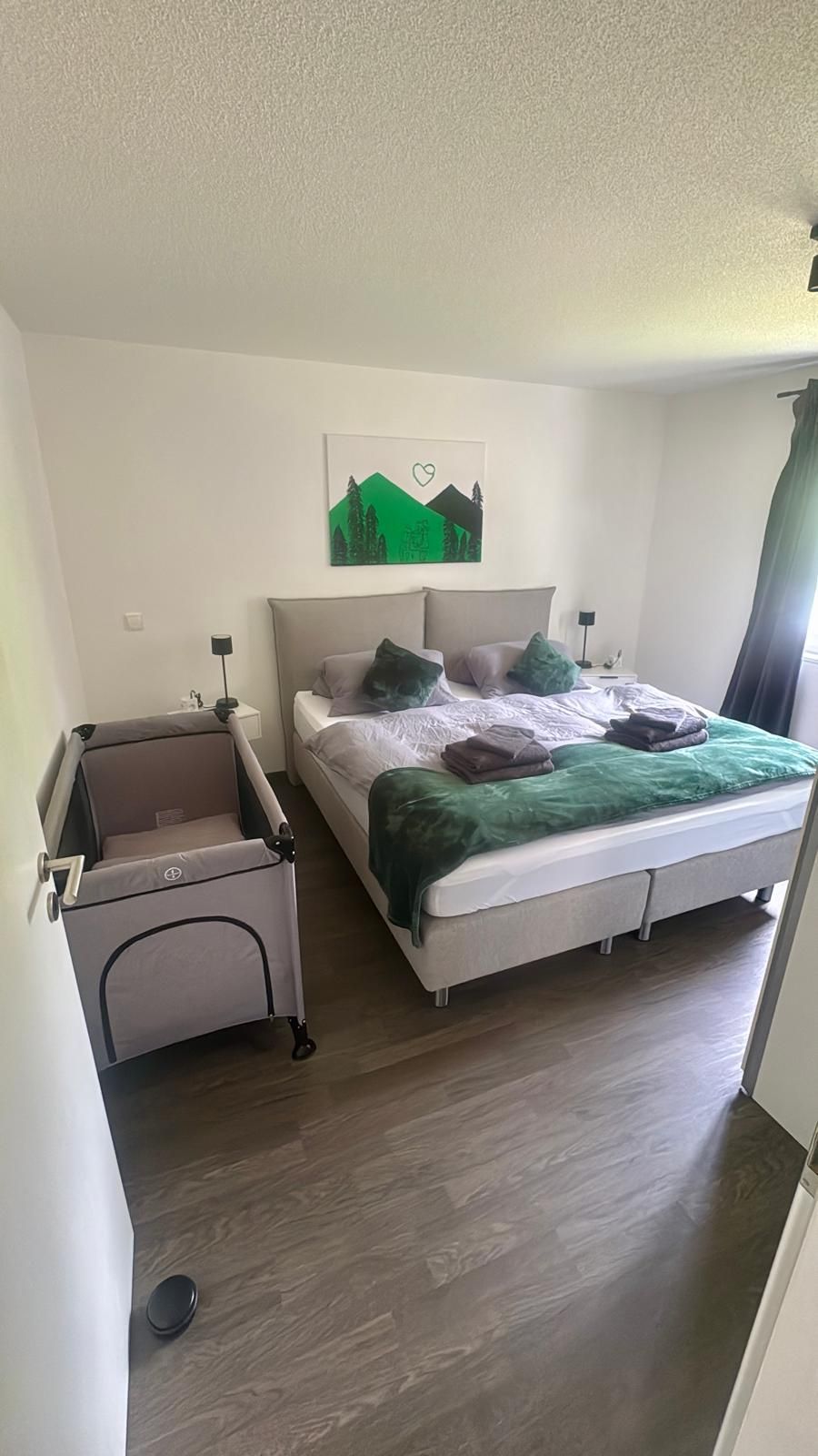 Familienfreundliches Schlafzimmer der Ferienwohnung in Feldberg mit großem Doppelbett und bereitgestelltem Baby-Reisebett