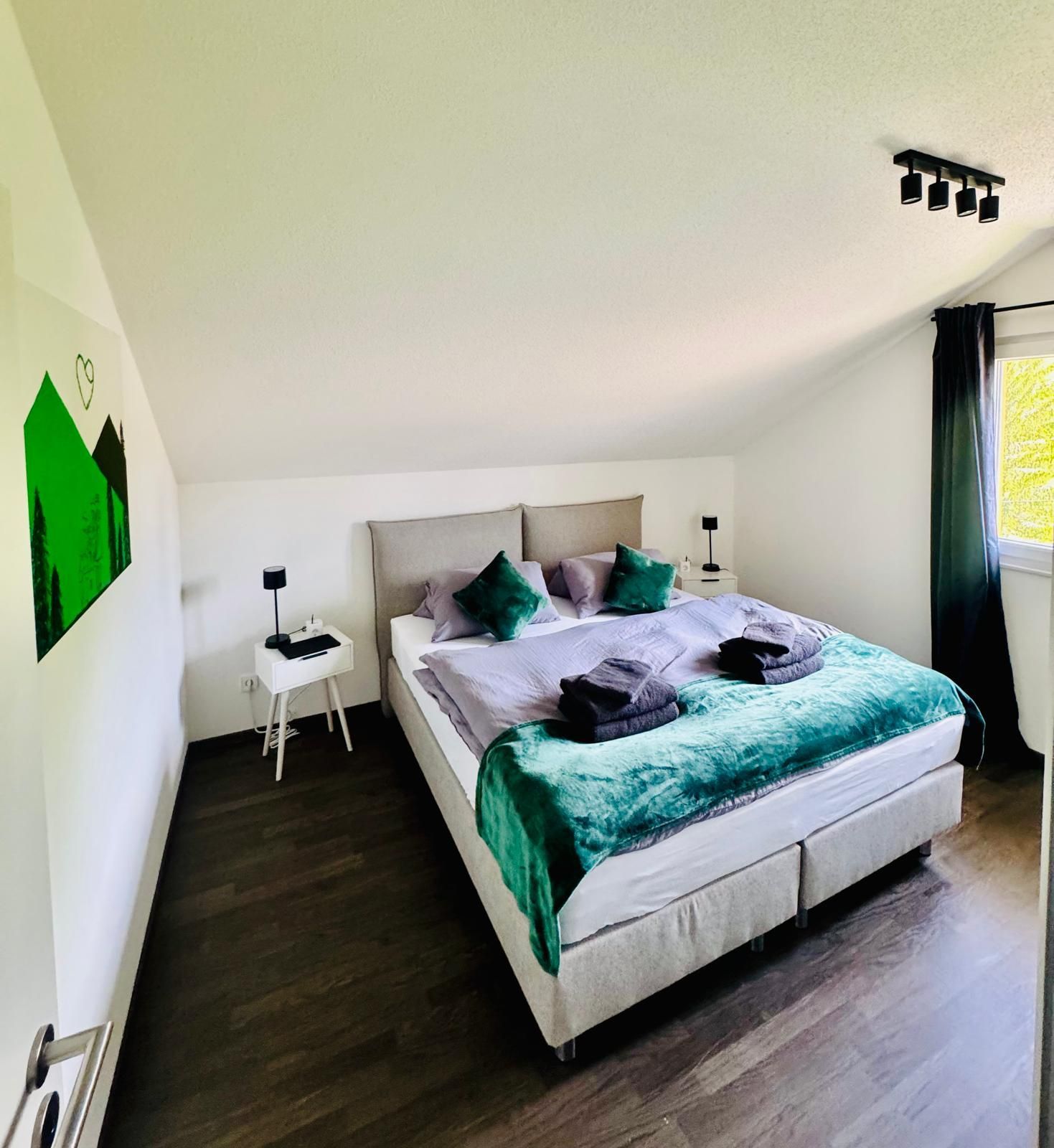 Gemütliches Schlafzimmer unter der Dachschräge mit modernem Schwarzwald-Kunstmotiv in der Ferienwohnung in Feldberg