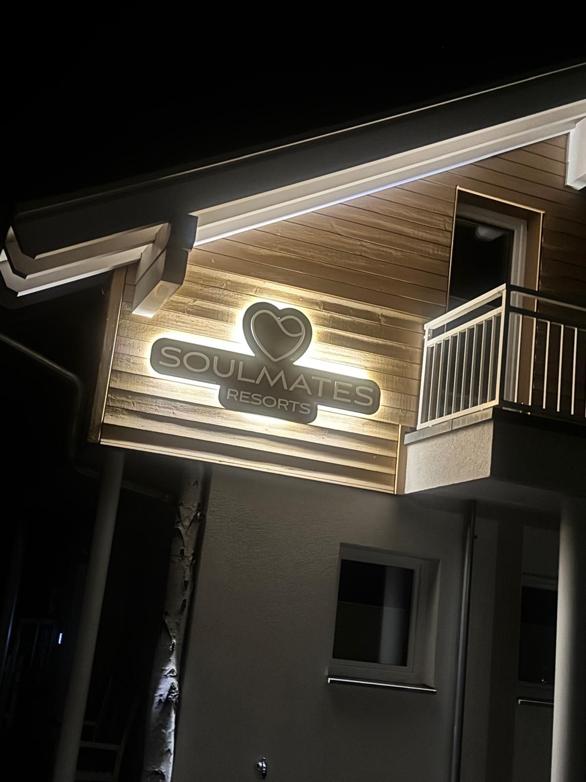 Beleuchtetes Logo von Soulmates Resorts an der Holzfassade der Ferienwohnung in Feldberg bei Nacht