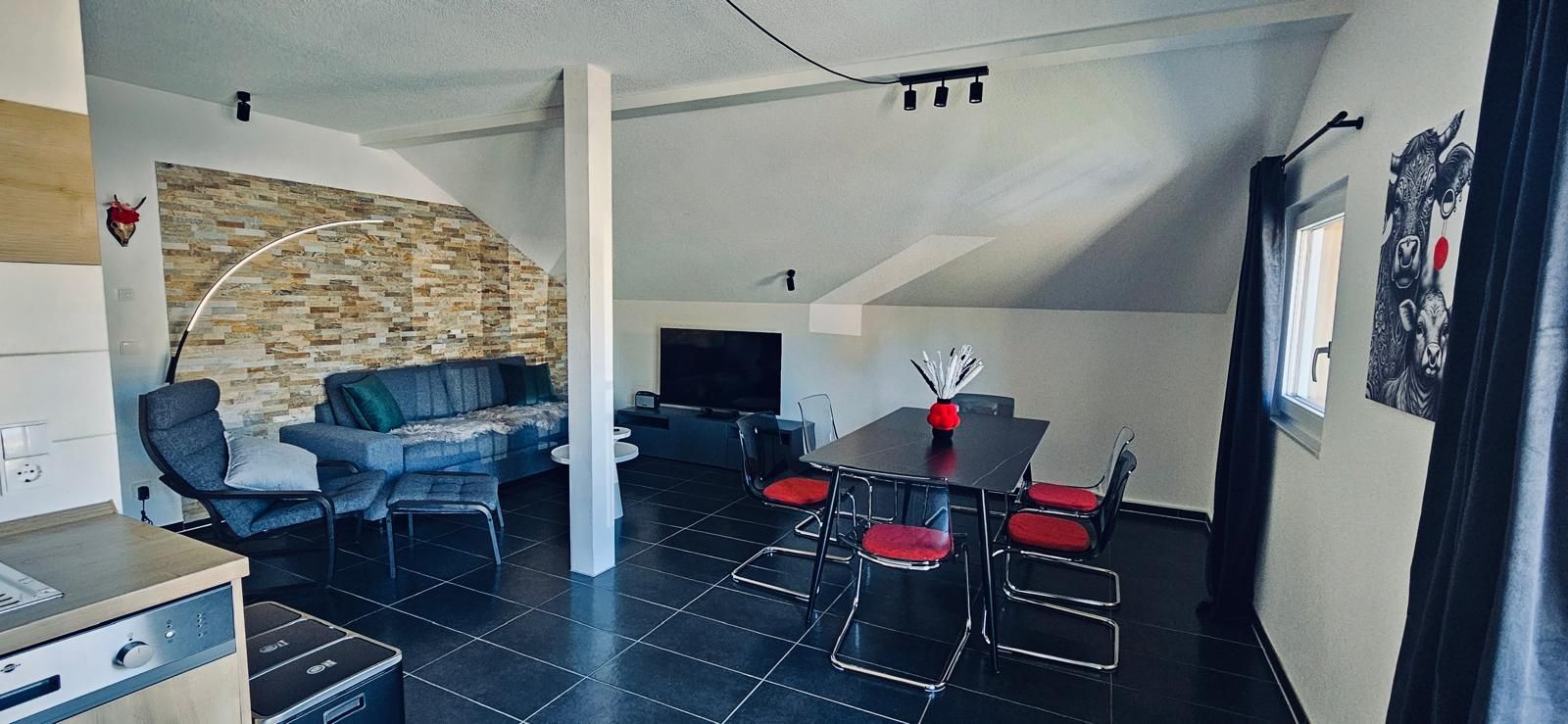 Großzügiger Wohn- und Essbereich mit gemütlicher Couch und markanter Steinwand in der Ferienwohnung in Feldberg