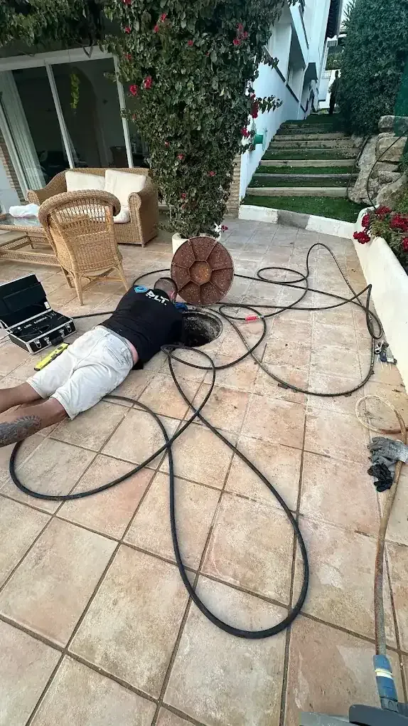 Hombre en el piso del patio rodeado de cables y equipos, posiblemente herido.