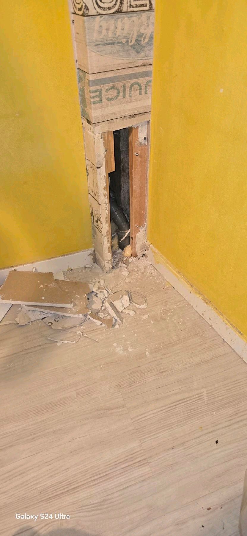 Loch in der Wand mit gelben Wänden und hellem Holzboden.