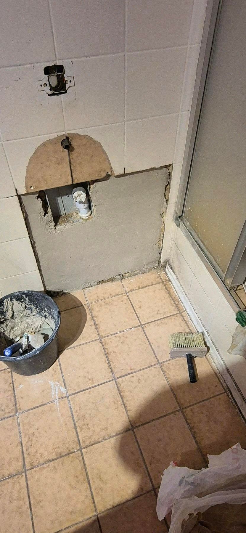 Badezimmer wird renoviert; freiliegende Rohrleitungen, kaputte Wandfliesen.