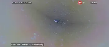 Inspektionskameraansicht im Inneren eines Rohrs mit einem dunklen Objekt in der Mitte und hellen Wänden.