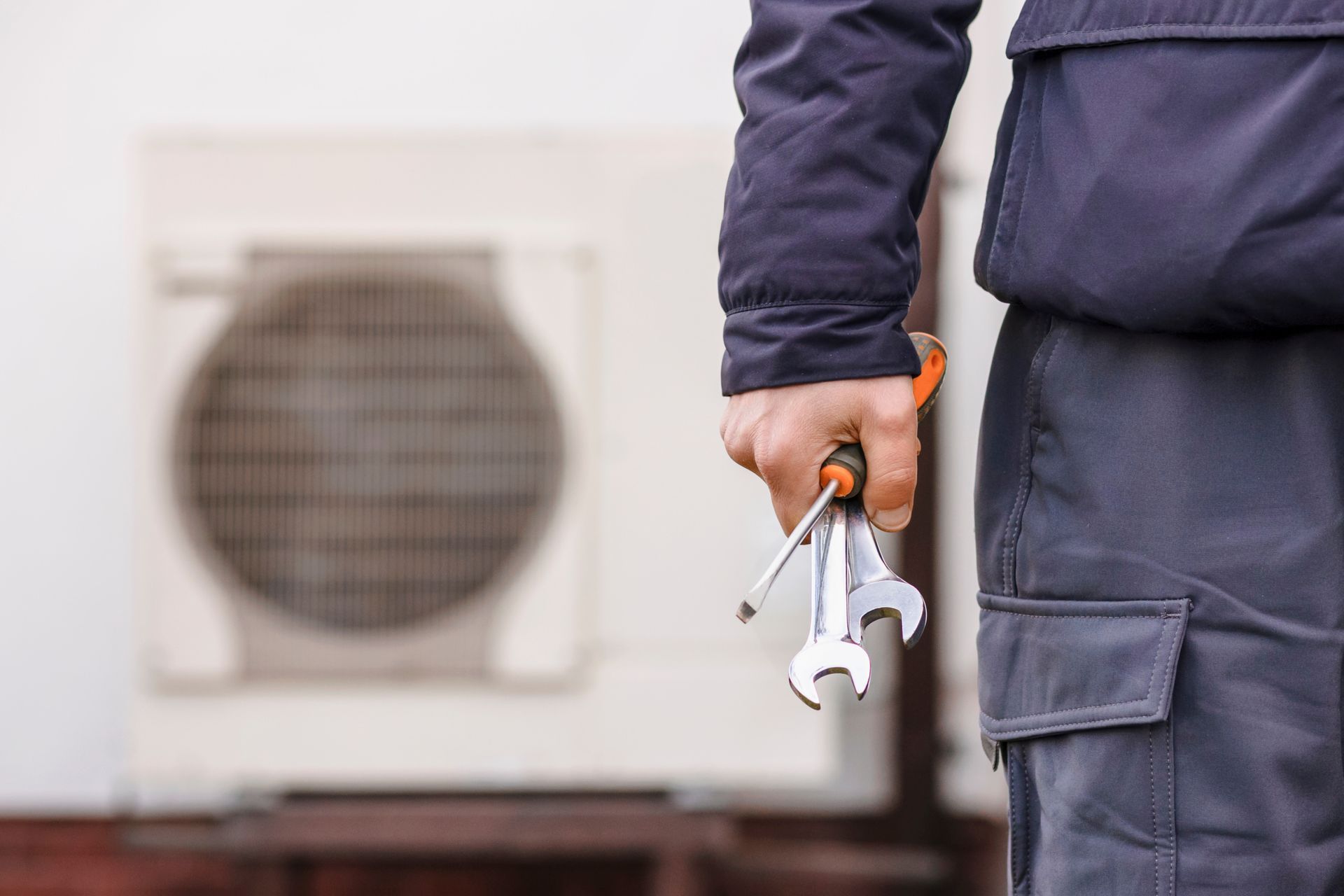 Un technicien tenant des outils à côté d'un climatiseur extérieur