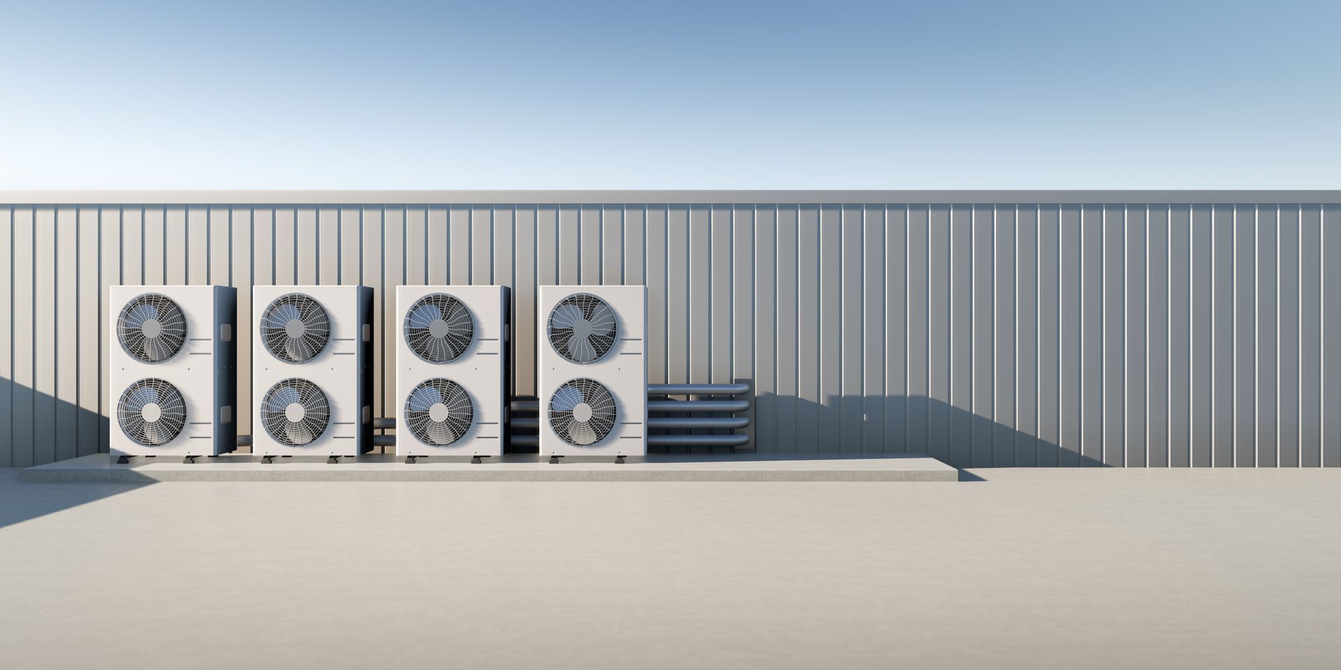 Quatre unités de climatisation extérieures contre une paroi métallique ondulée.