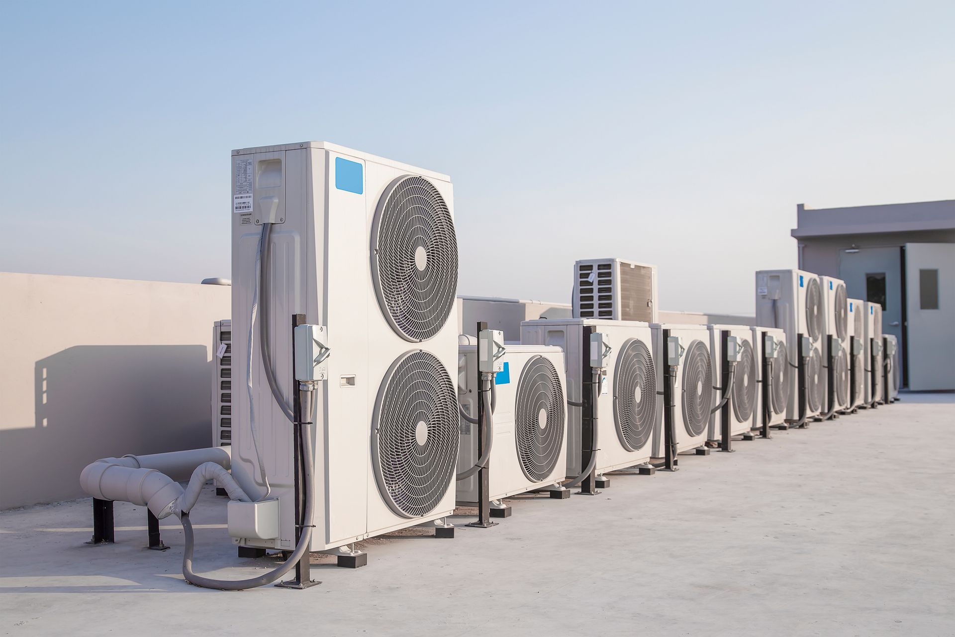 Rangée d'unités de climatisation sur un toit plat sous un ciel dégagé.