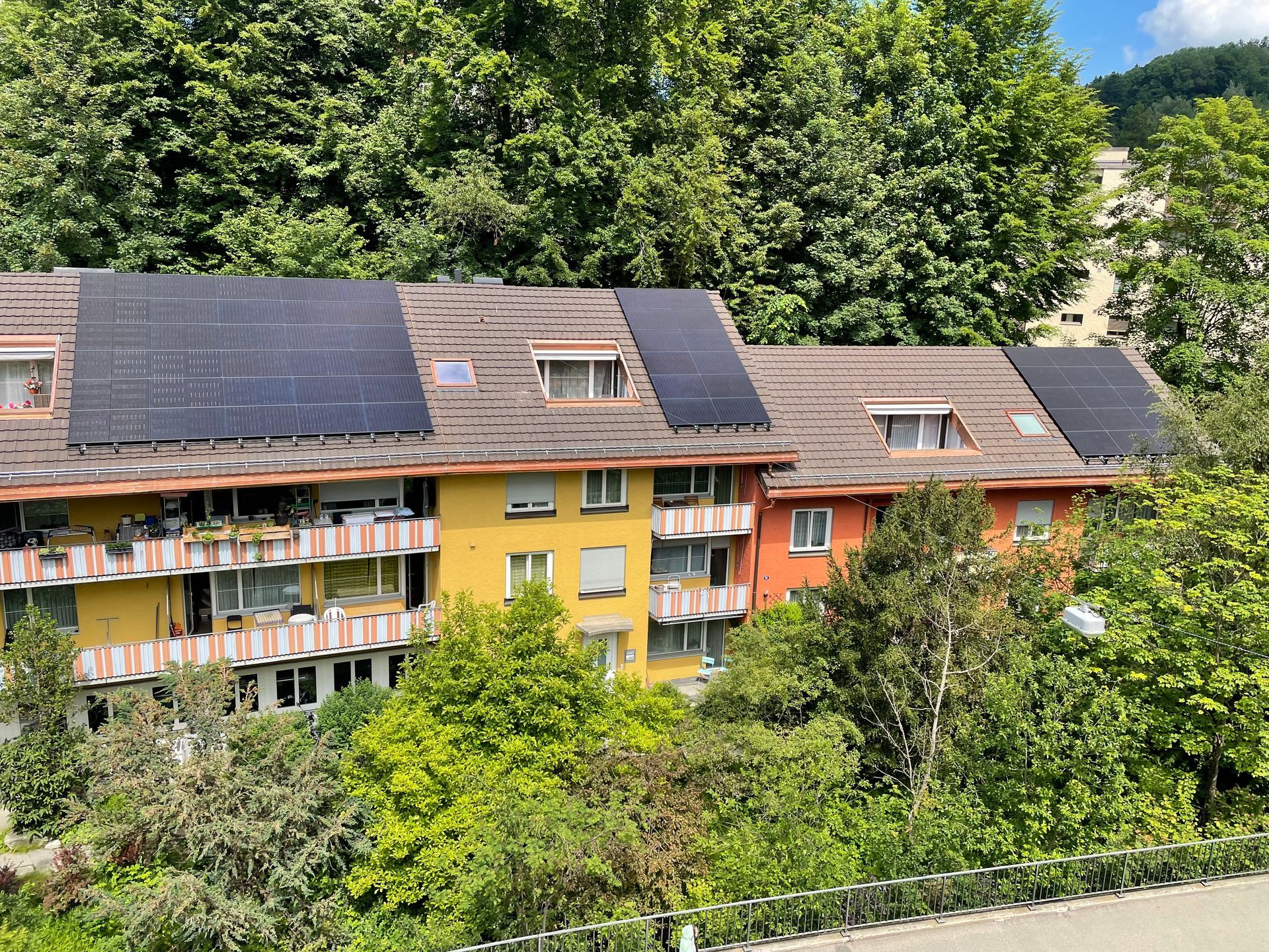 Modernes Haus mit Solarzellen auf dem Dach unter strahlend blauem Himmel.