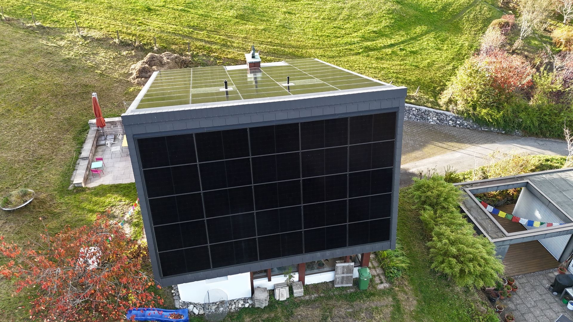 Auf einem Dach mit grauen Schindeln und Kupferverkleidung installierte Solarmodule.