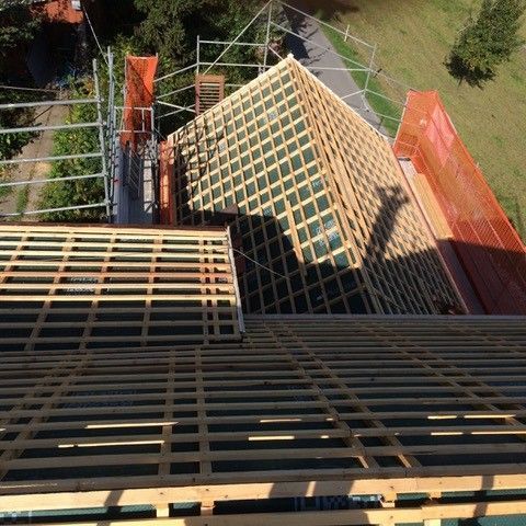 An einem sonnigen Tag wird mit einem Hochdruckreiniger ein braunes Ziegeldach besprüht und Schmutz entfernt.