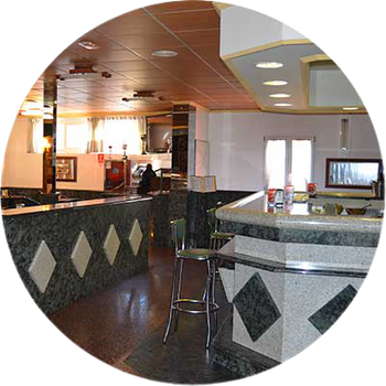 Un restaurante con barra y taburetes en círculo.