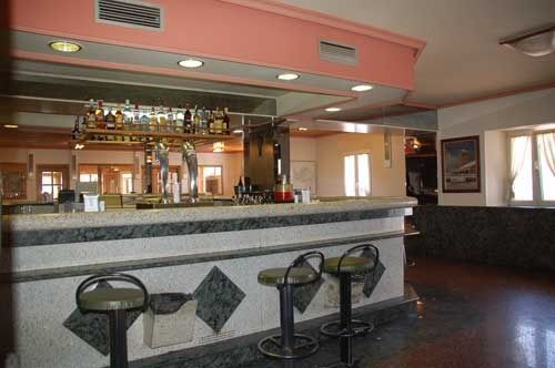 Una barra en un restaurante con taburetes y una encimera de mármol.