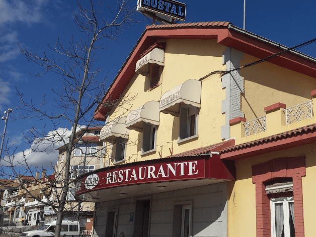 Un edificio amarillo con un cartel rojo que dice restaurante.