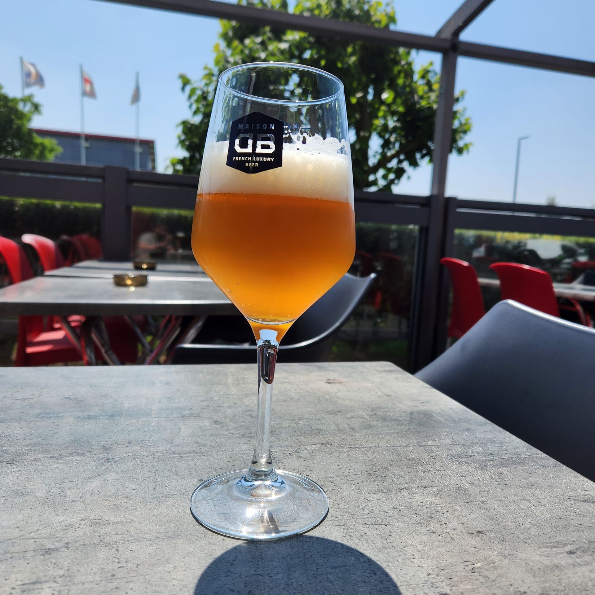 Un verre de bière sur une table en terrasse. Bière blonde à la mousse blanche.