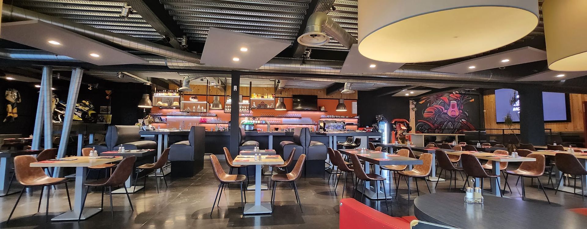 Vue intérieure d'un restaurant moderne avec tables, chaises et coin bar.