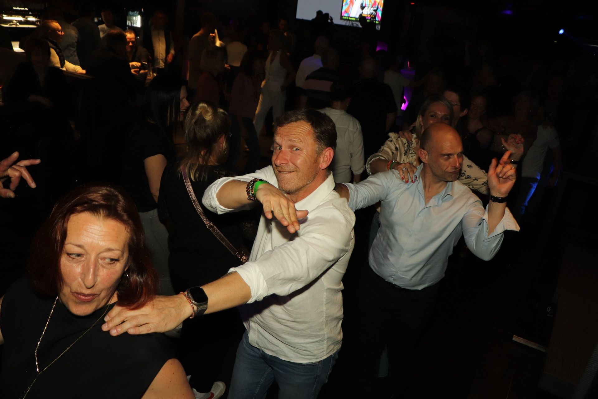 Des gens dansent dans la brasserie privatisée. Deux hommes en chemise blanche sourient.