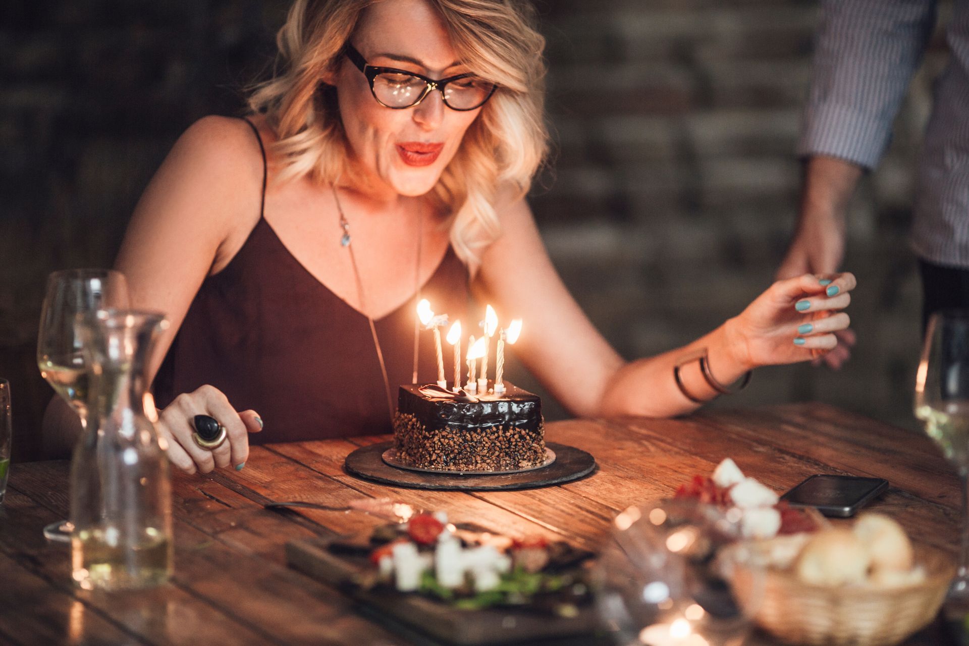 Une femme souffle les bougies d'un petit gâteau sur une table, fêtant un anniversaire.