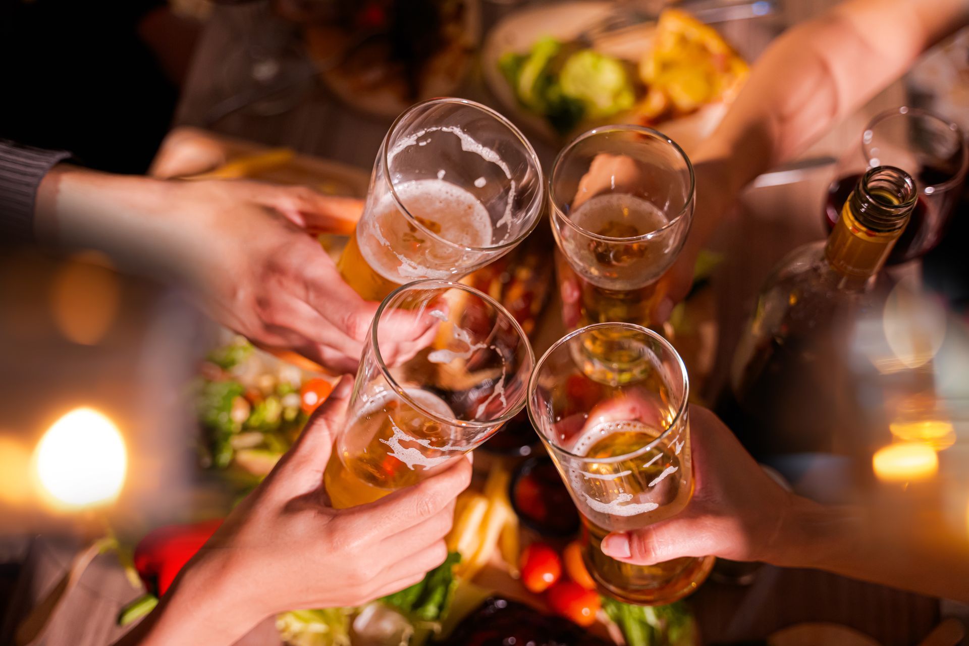 Des mains qui s'entrechoquent avec des verres de bière et de vin.