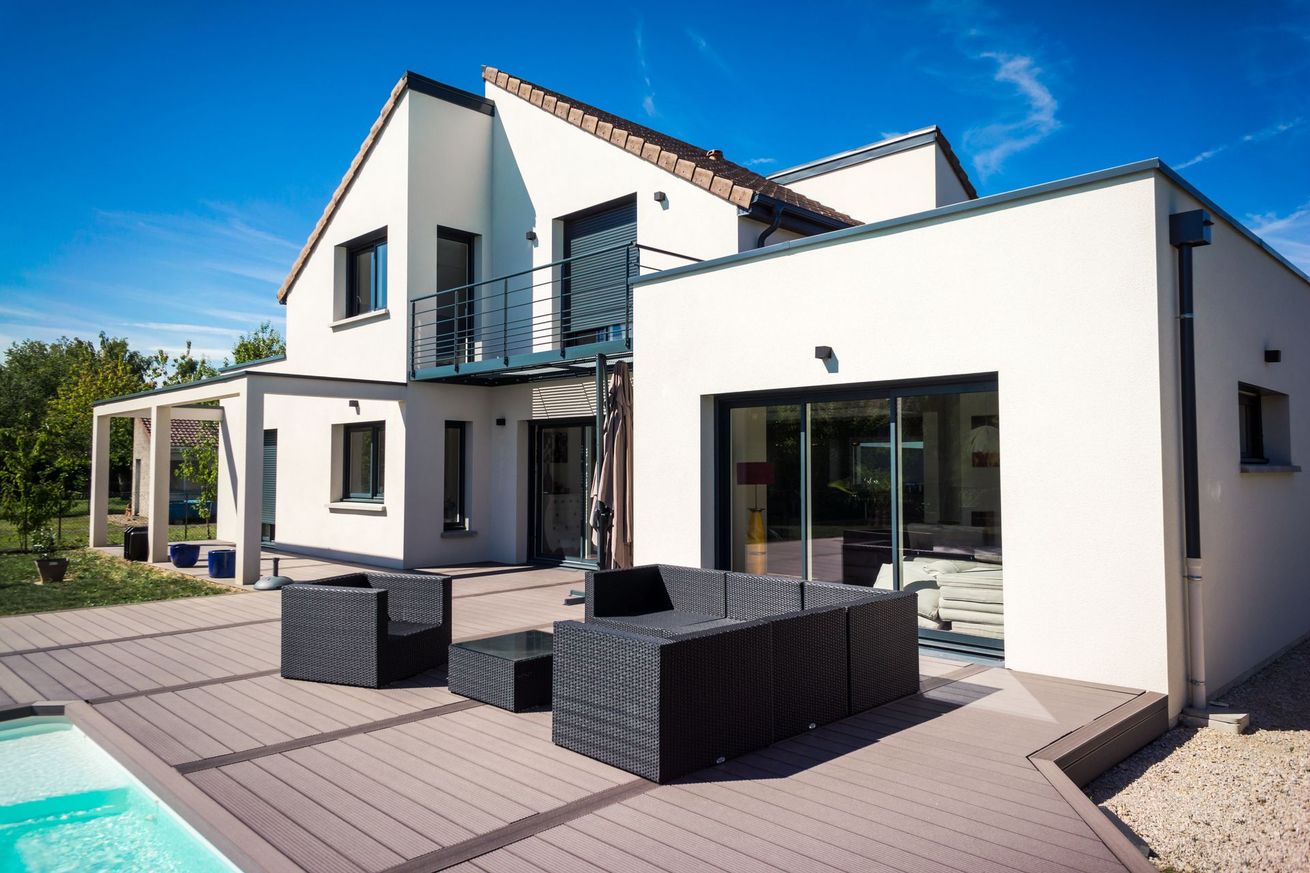 Maison blanche moderne avec des finitions noires et une terrasse ensoleillée