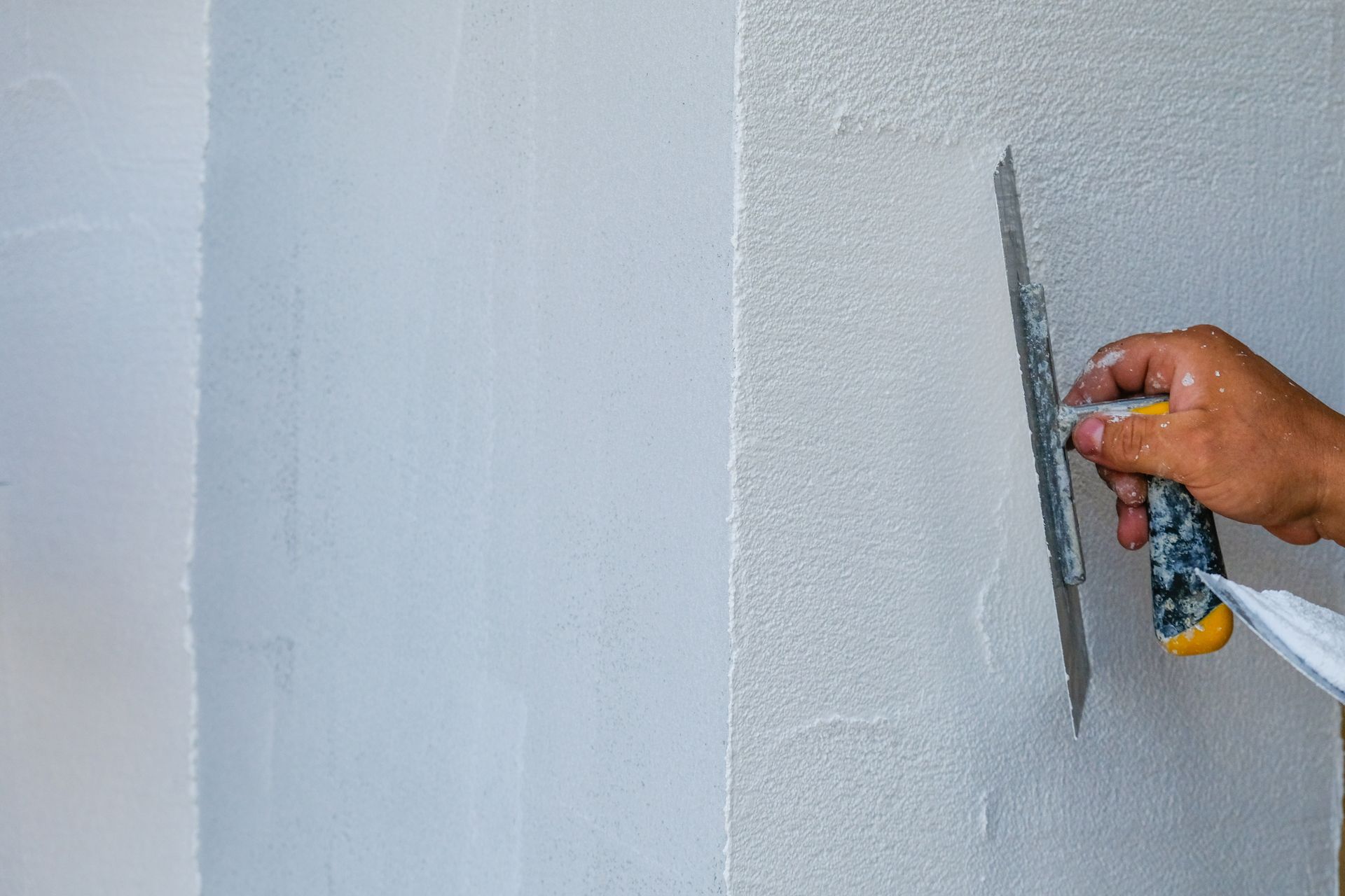Lissage manuel d'un enduit blanc frais sur un mur à l'aide d'une truelle