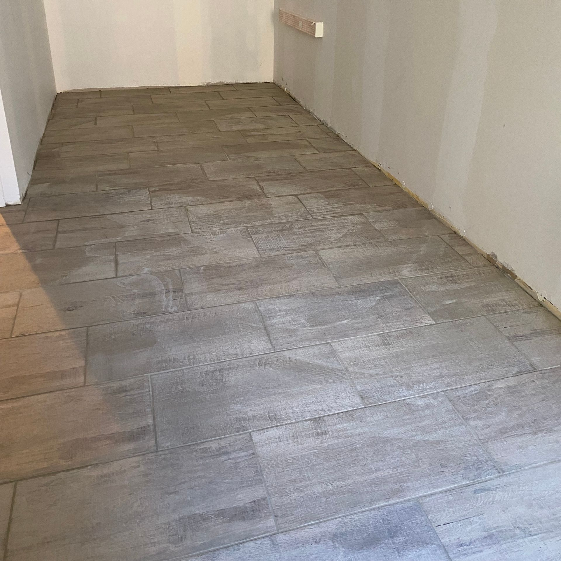 Parquet flottant gris dans une petite pièce aux murs blancs.
