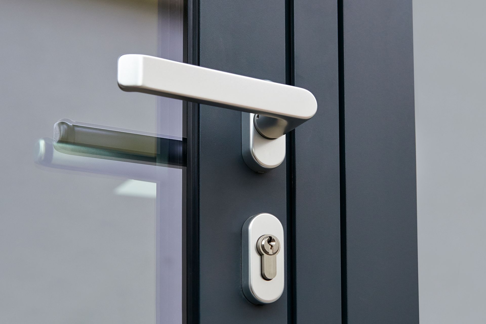 Gros plan sur une poignée de porte métallique et une serrure sur une porte en verre foncé