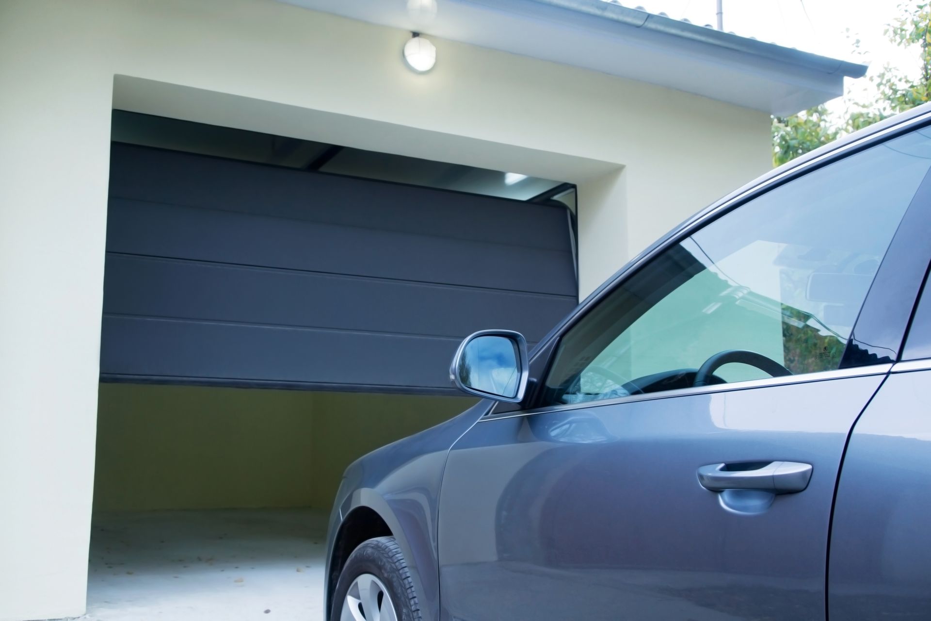 Voiture bleue garée devant un garage, porte entrouverte