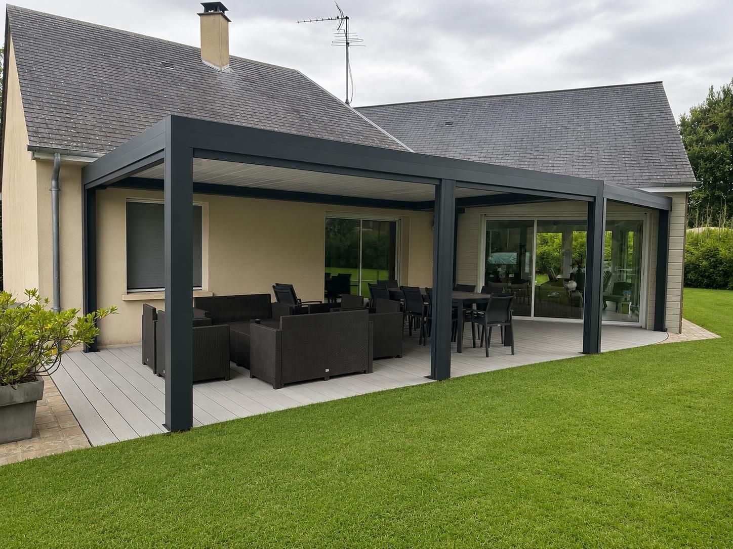 Pergola bioclimatique attenante à une maison avec salon de jardin et espace repas sur la terrasse