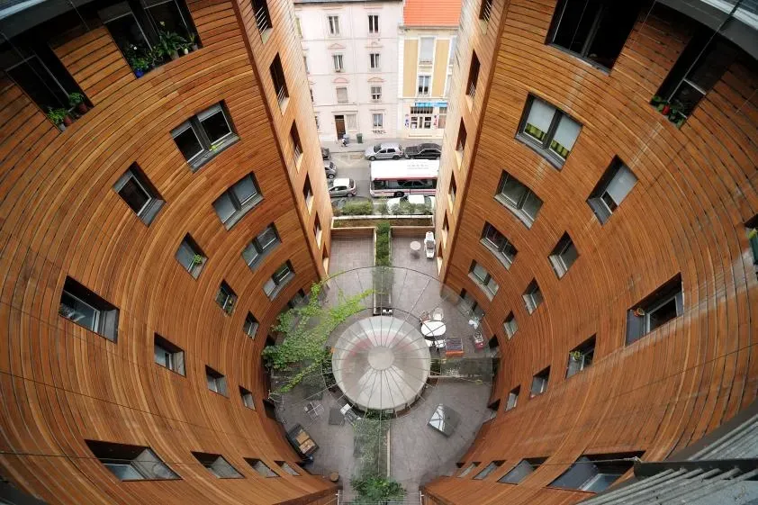 Prise de vue en plongée d'un bâtiment en bois incurvé entourant une cour centrale.