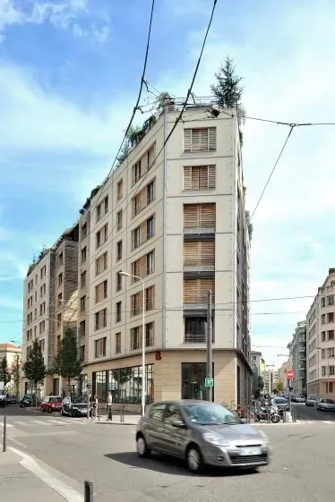 Un immeuble d'appartements clair avec un angle arrondi dans une rue.