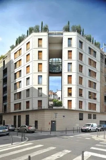 Immeuble d'appartements moderne à plusieurs étages avec une grande ouverture centrale, doté d'un jardin sur le toit.