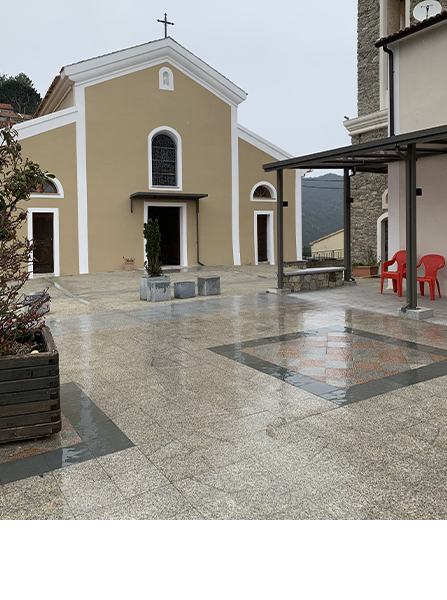 Église à la façade beige, couronnée d'une croix, et à l'esplanade en pierre humide.