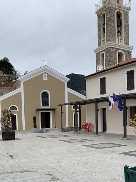 Église à façade beige et haut clocher en pierre sur une place de ville, Corse.