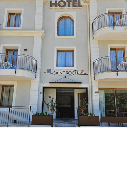 Entrée de l'hôtel Saint-Roch avec portes ouvertes. Bâtiment gris clair avec balcons, enseigne « HOTEL » et logo.
