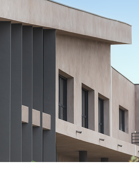 Bâtiment moderne avec des accents gris, des murs en stuc clair et des fenêtres rectangulaires.