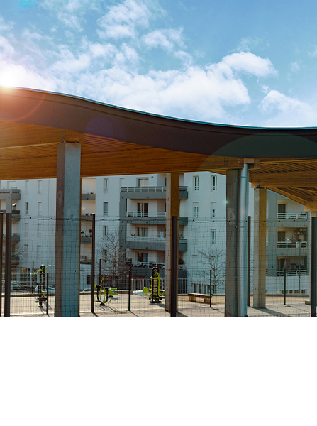 Passerelle couverte avec en arrière-plan un immeuble d'habitation et un ciel bleu.