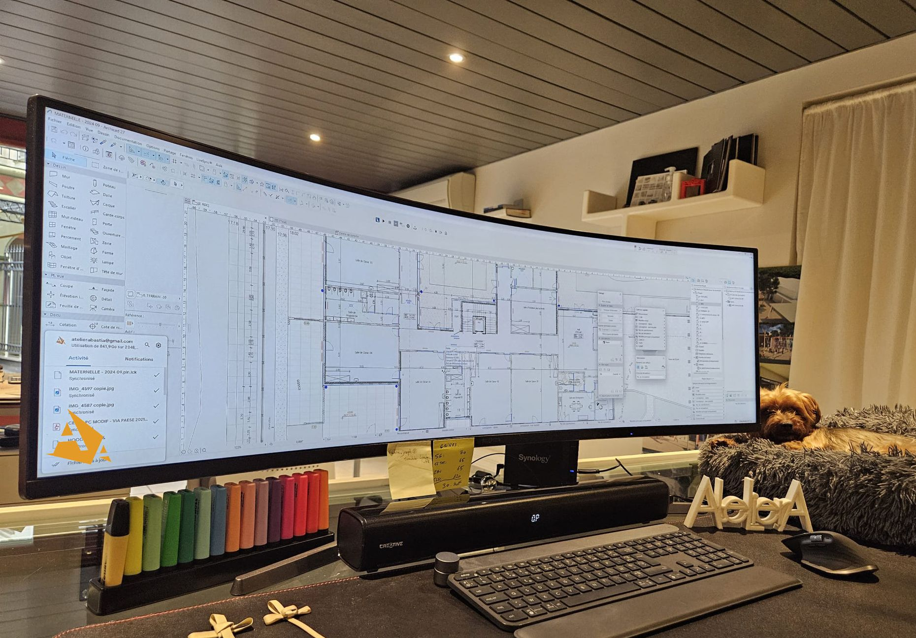 Écran ultra-large et incurvé affichant des plans architecturaux, sur un bureau avec clavier.
