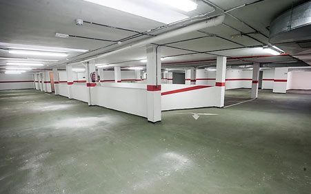 Un aparcamiento subterráneo vacío con rayas rojas y blancas en las paredes.