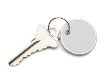 Una llave con un llavero adherido a ella sobre un fondo blanco.