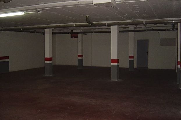 Un estacionamiento vacío con pilares rojos y blancos