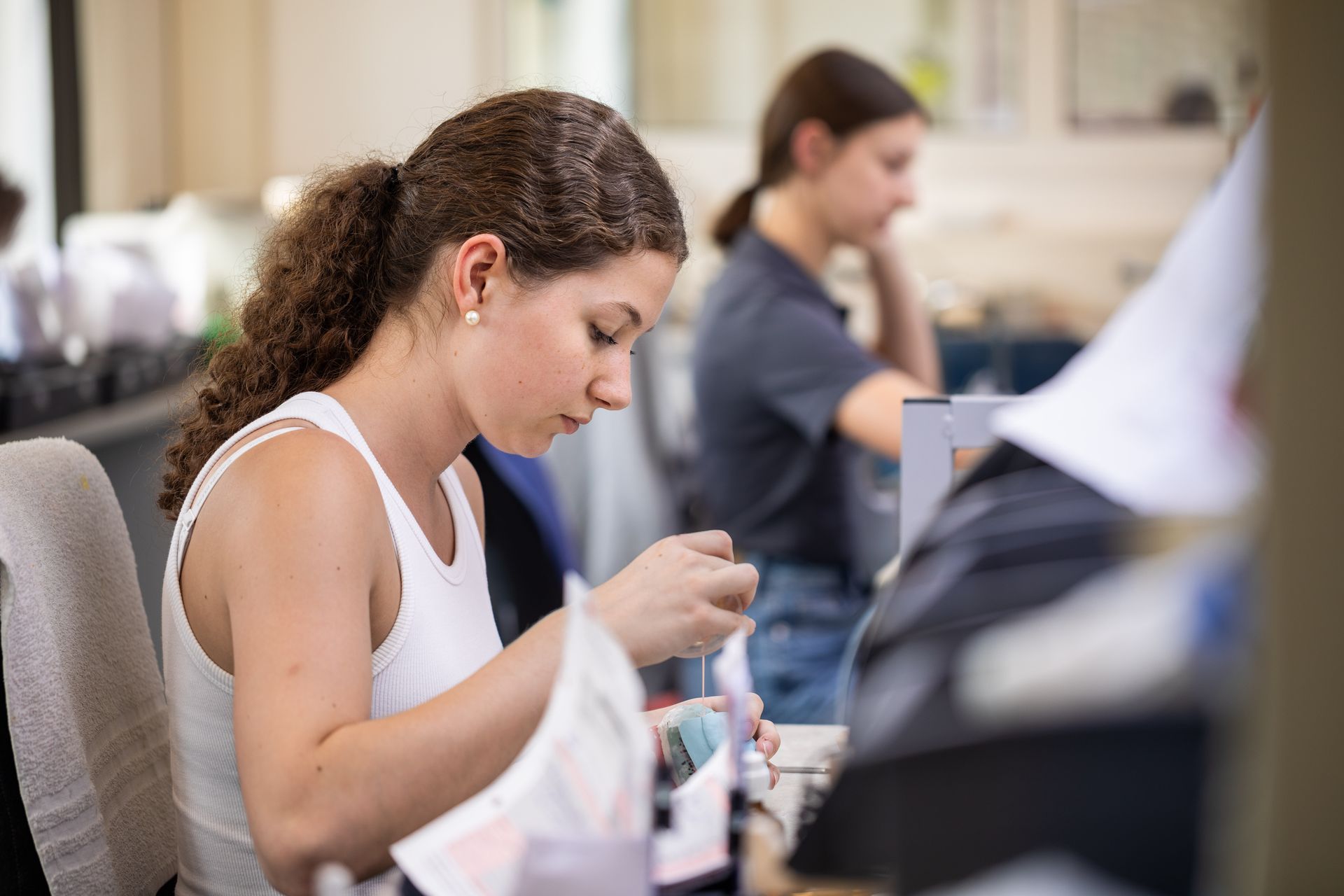 Zahntechnikerin sitzt an einem Tisch und arbeitet